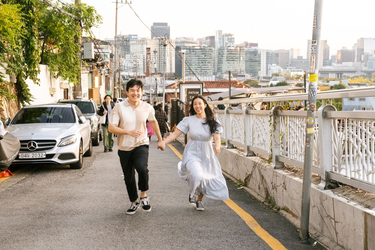 Urban cityscape with walking path along waterfront with tall buildings in background.