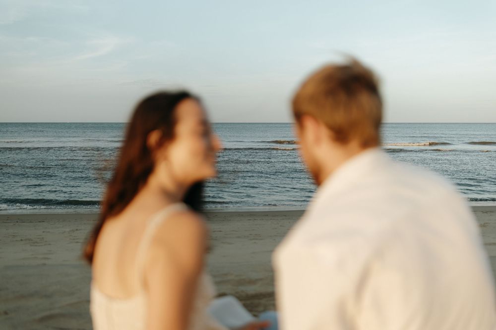 Silhouetted couple embraces romantically at sunset on the beach in a series of candid beach wedding photos.