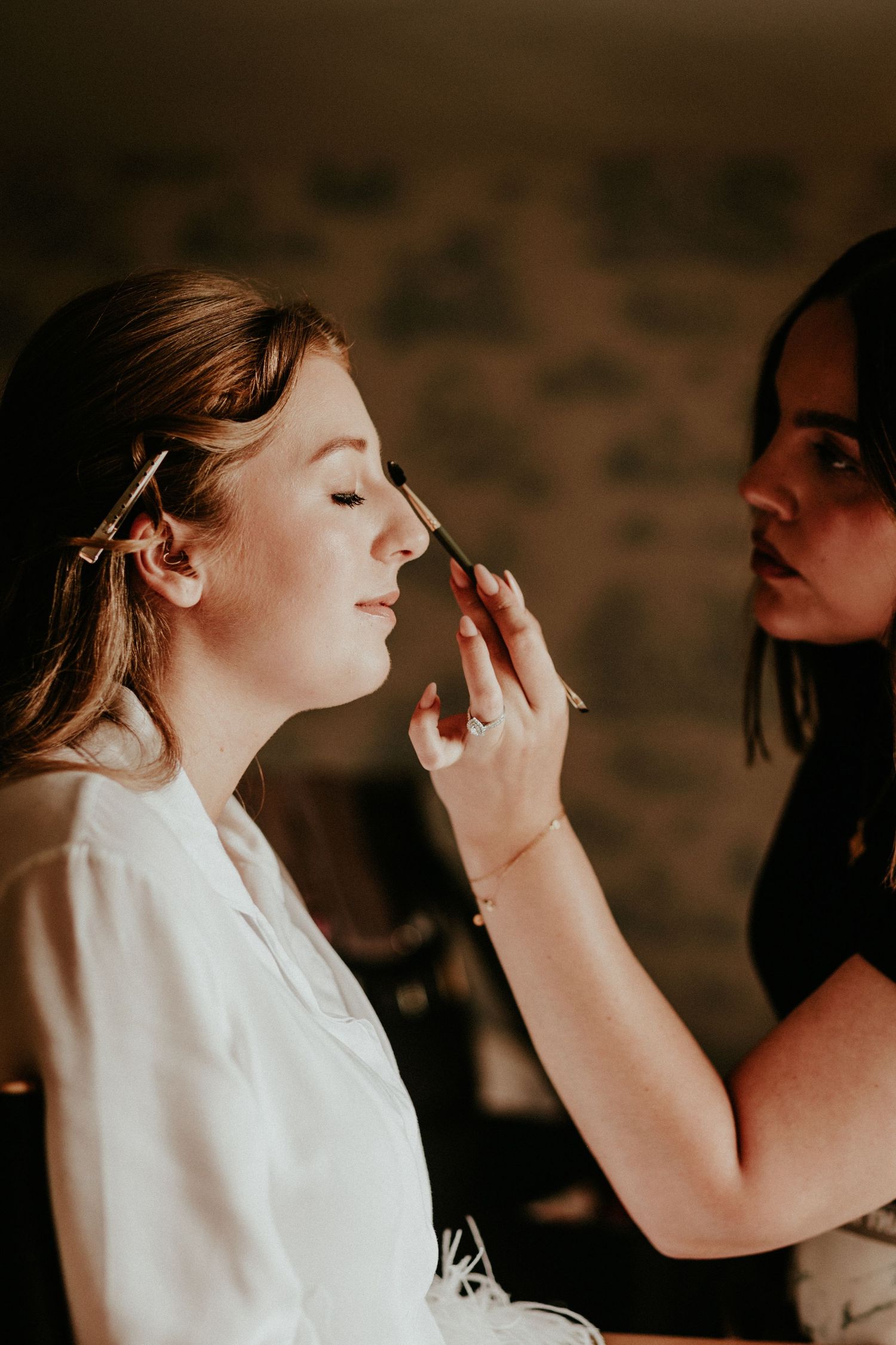 A series of candid shots showing makeup being applied to someone wearing white in a warm-toned setting.
