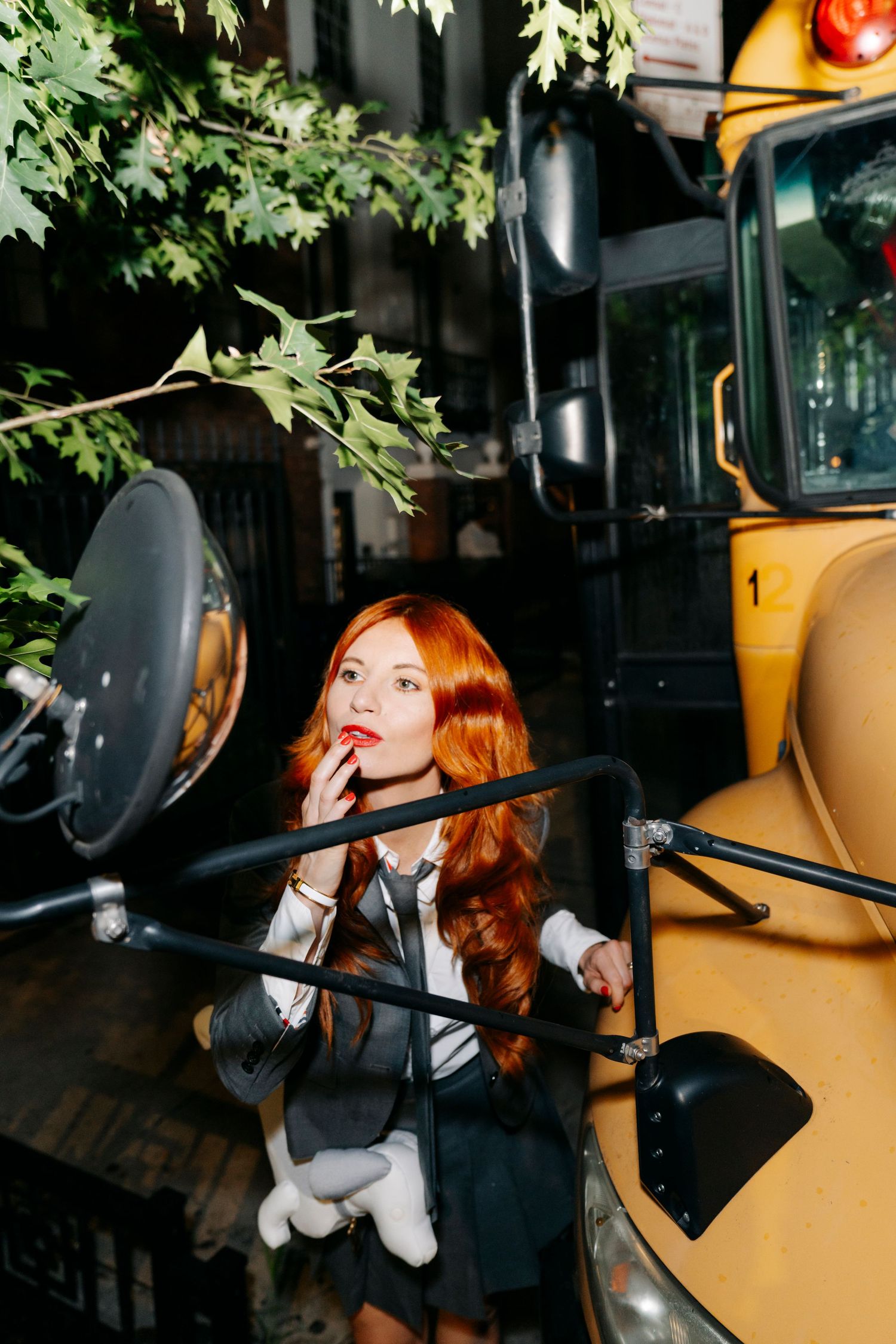 A person in black business attire poses pensively in different positions inside a vehicle with tan leather seats.