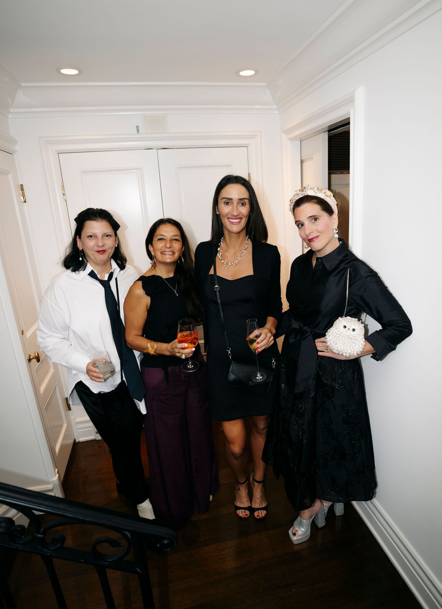 A group wearing black and white outfits pose together at a social gathering in an indoor setting.