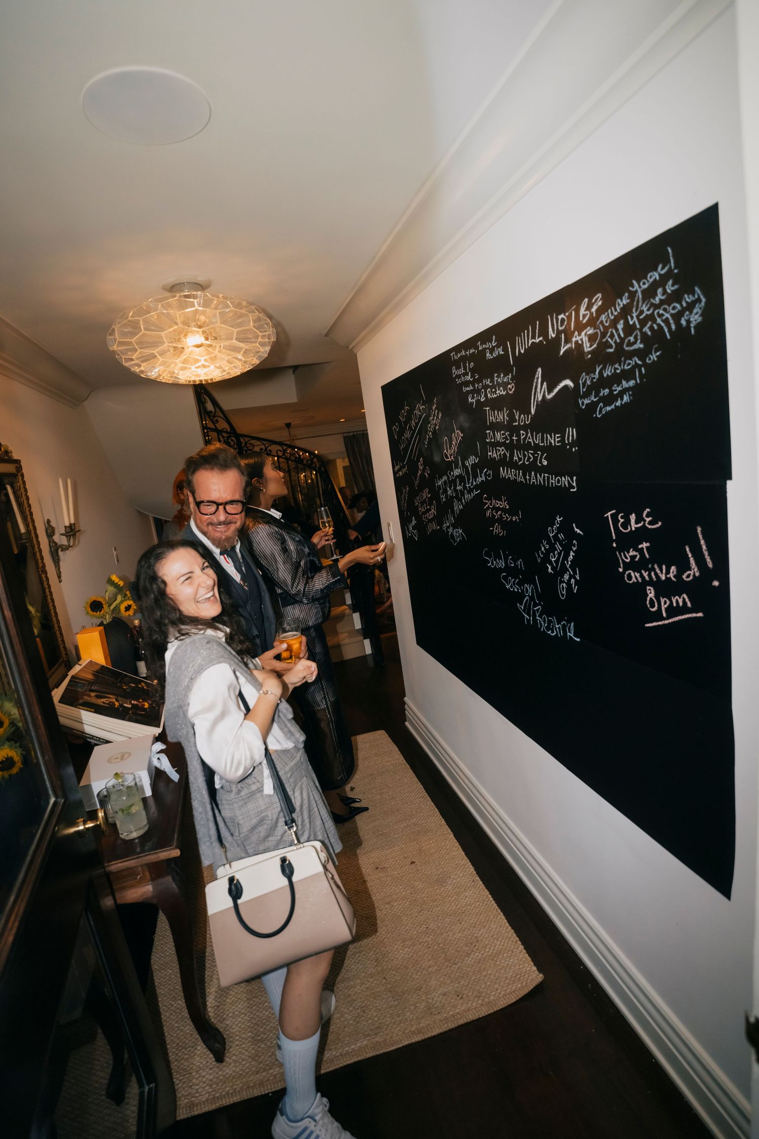 People gathering in a room with black chalkboard walls covered in writing.