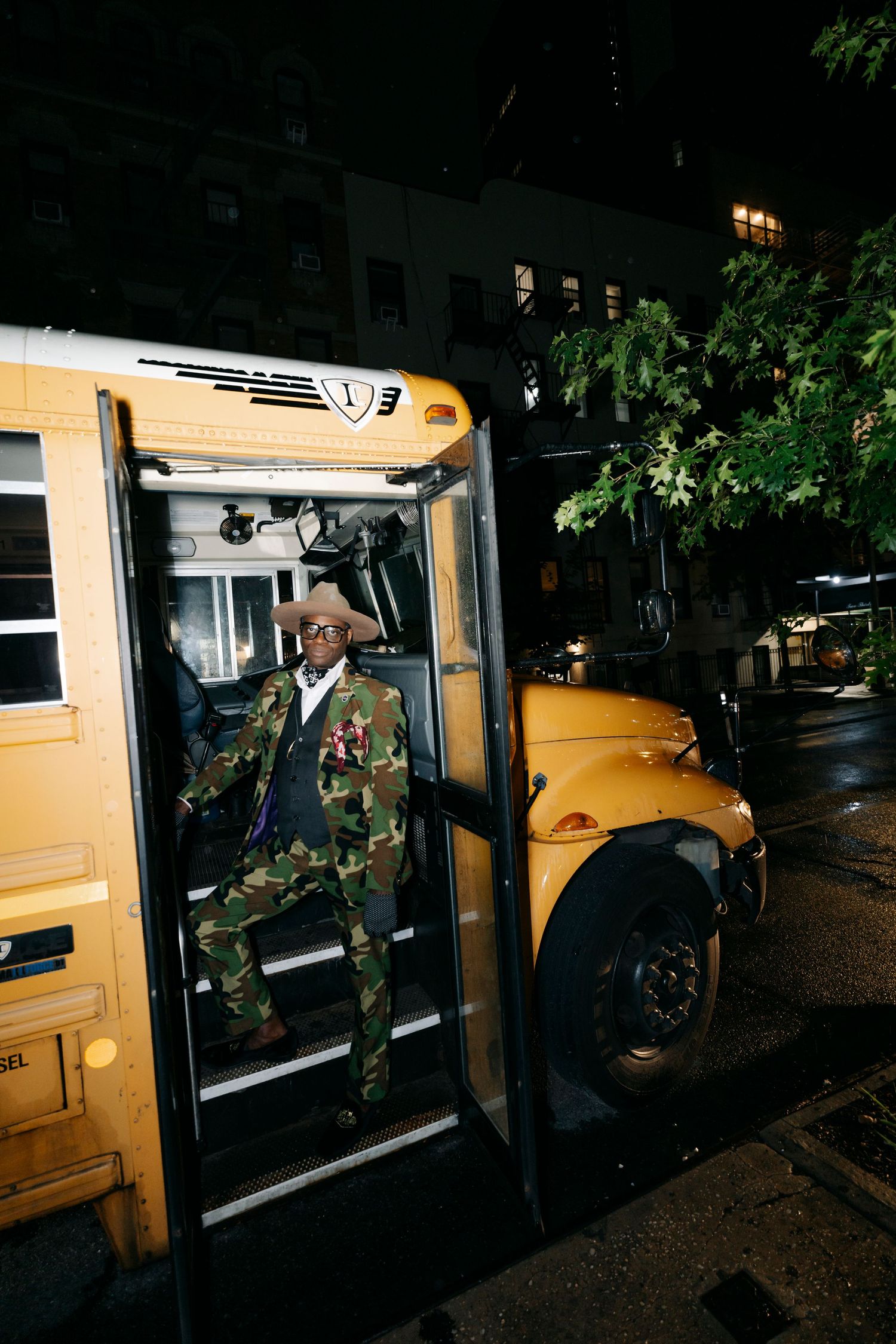 Yellow school bus illuminated at night with passengers entering and exiting.
