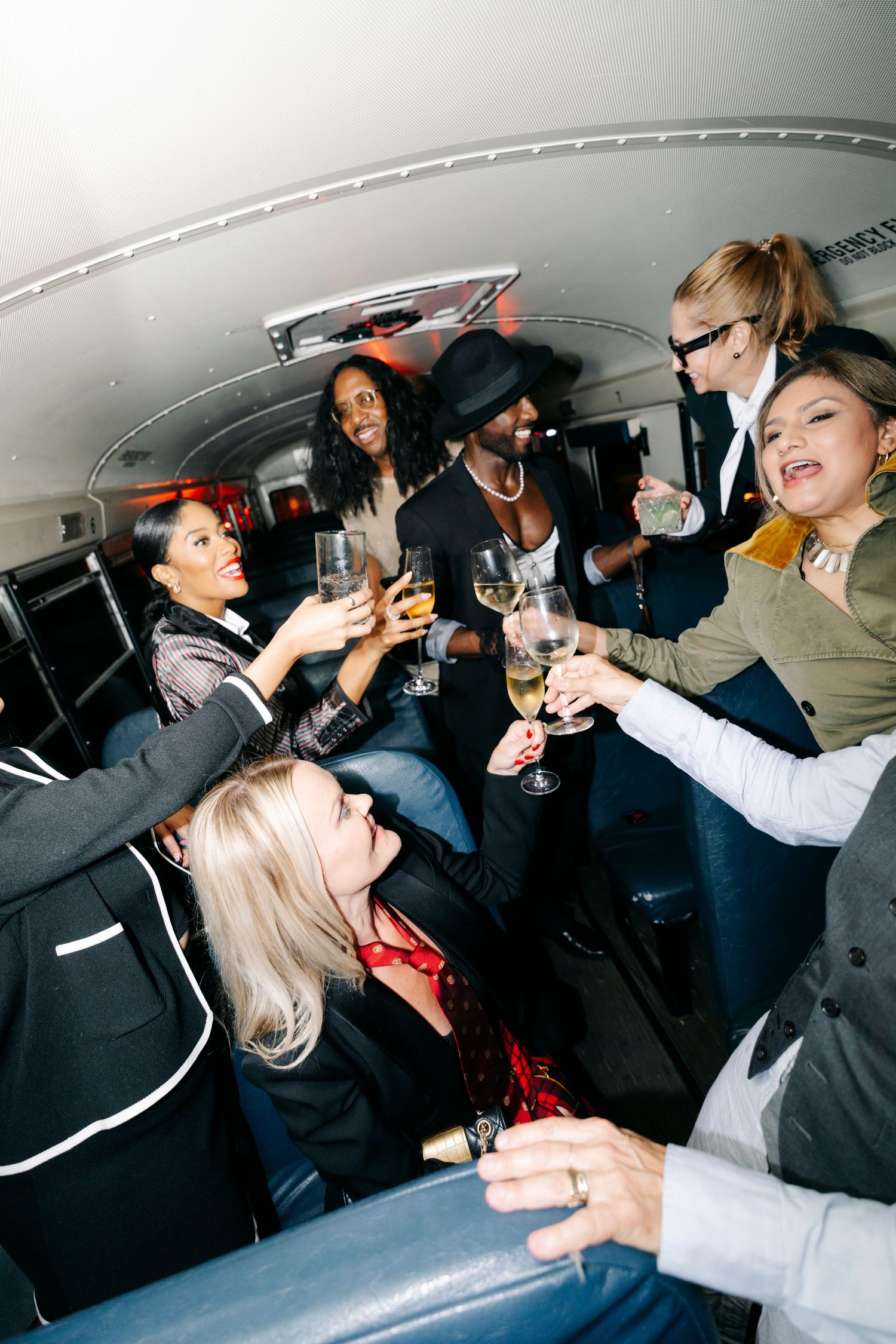 Party guests celebrating in formal attire inside a crowded party bus.