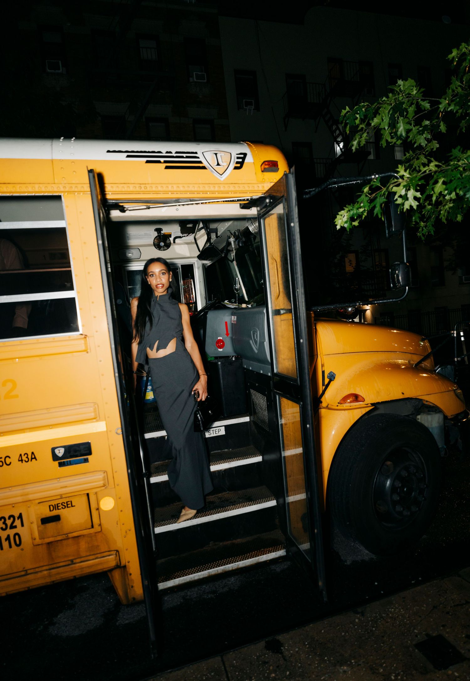 Group poses by classic yellow school bus at night.