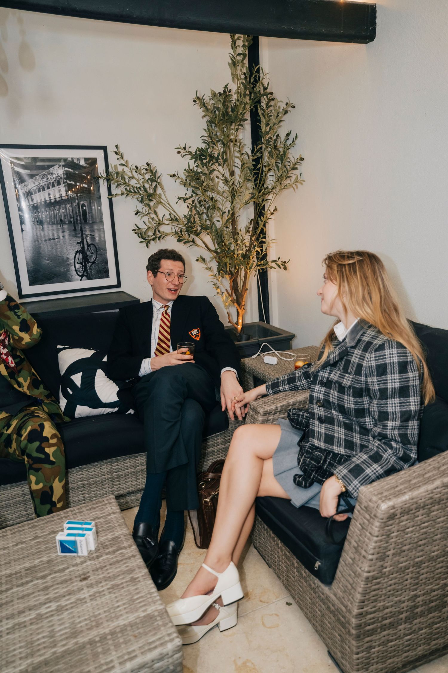 Two people having a business conversation while sitting on wicker furniture in a modern office space.
