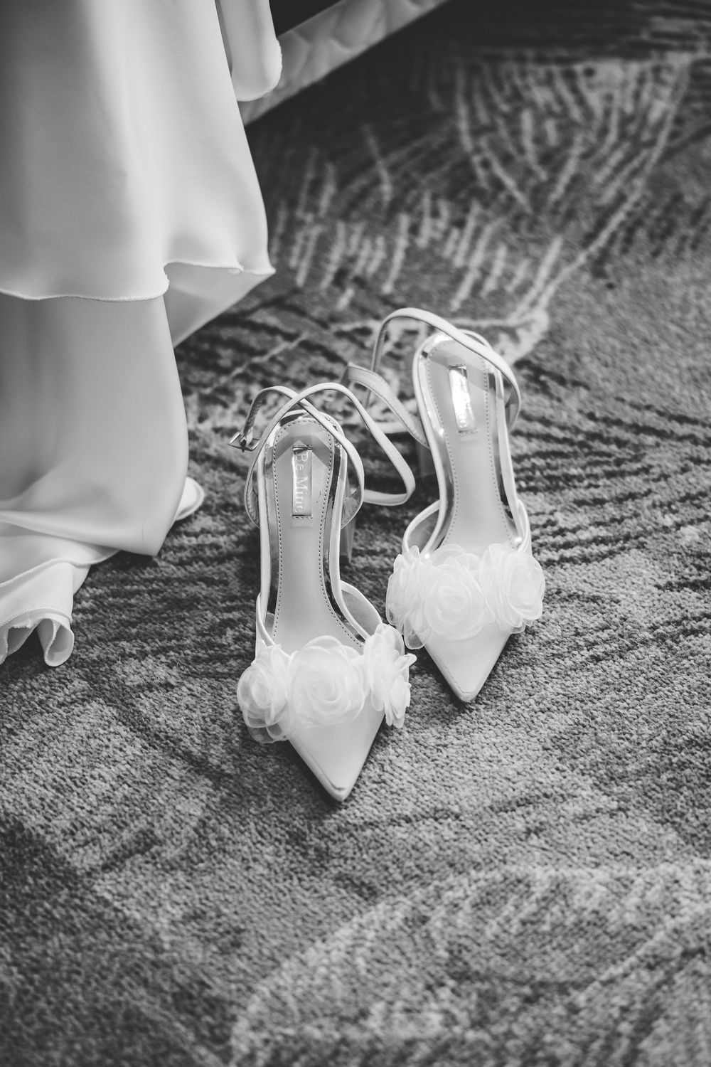 Black and white sequence of elegant bridal shoes with rosettes photographed on textured carpet.