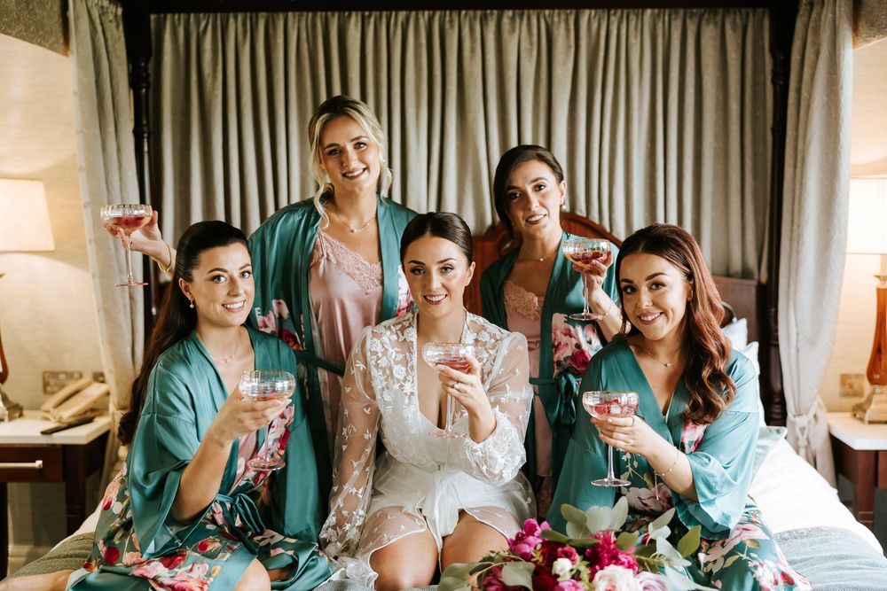 Wedding preparation scene with bridesmaids in teal dresses sitting together in a bridal suite.