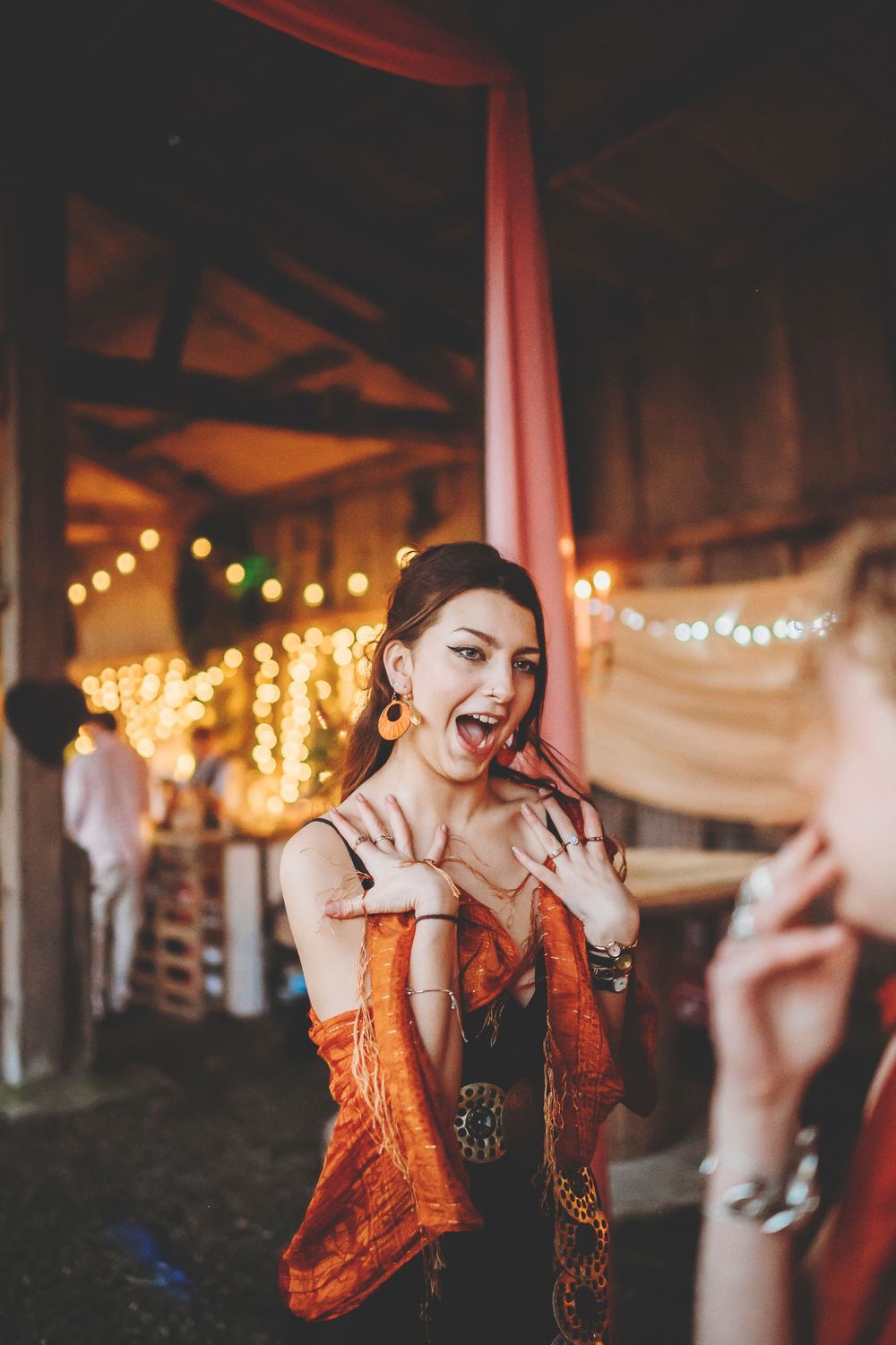 People dancing and singing together in a festive decorated indoor venue with string lights.