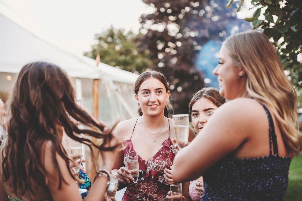 People enjoying an outdoor celebration with drinks and laughter in a warm, festive atmosphere.