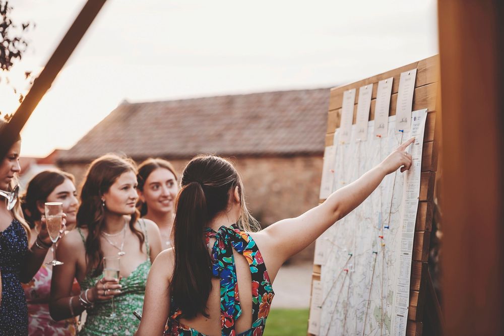 Group of women laughing joyfully together while looking at white writing board during outdoor gathering.