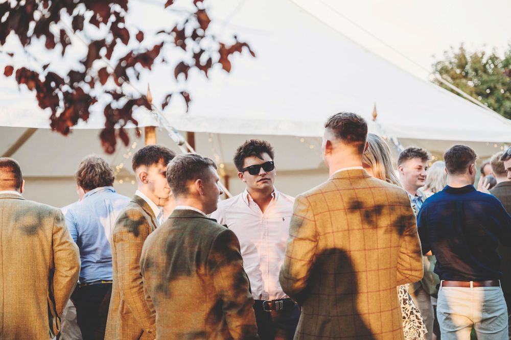 People gathered outdoors for a sunny event with autumn trees in the background creating a festive atmosphere.