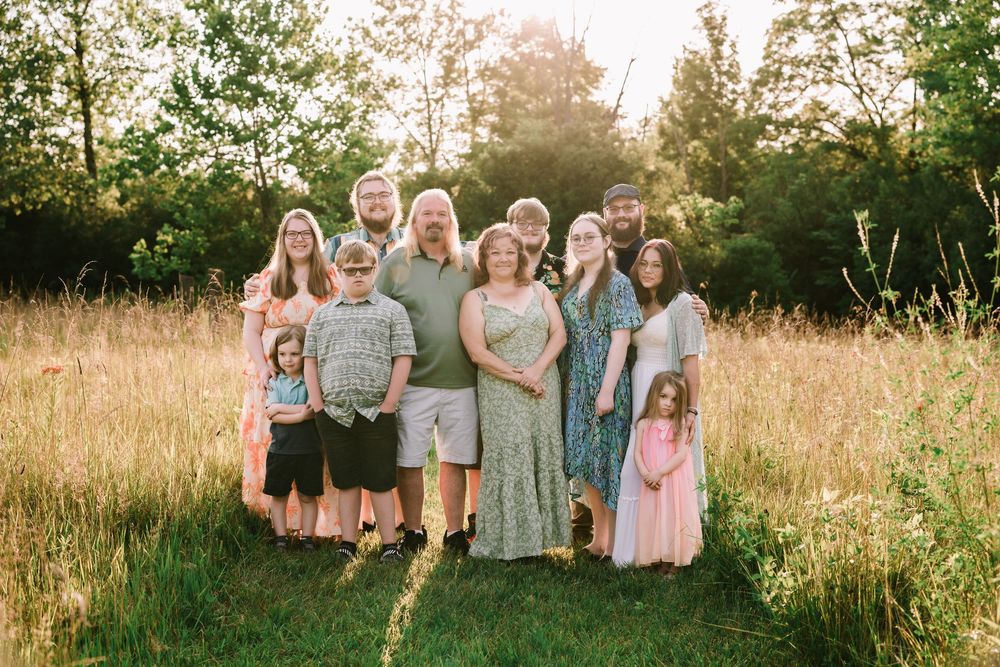 Family group portrait in a summer meadow with golden sunlight filtering through.
