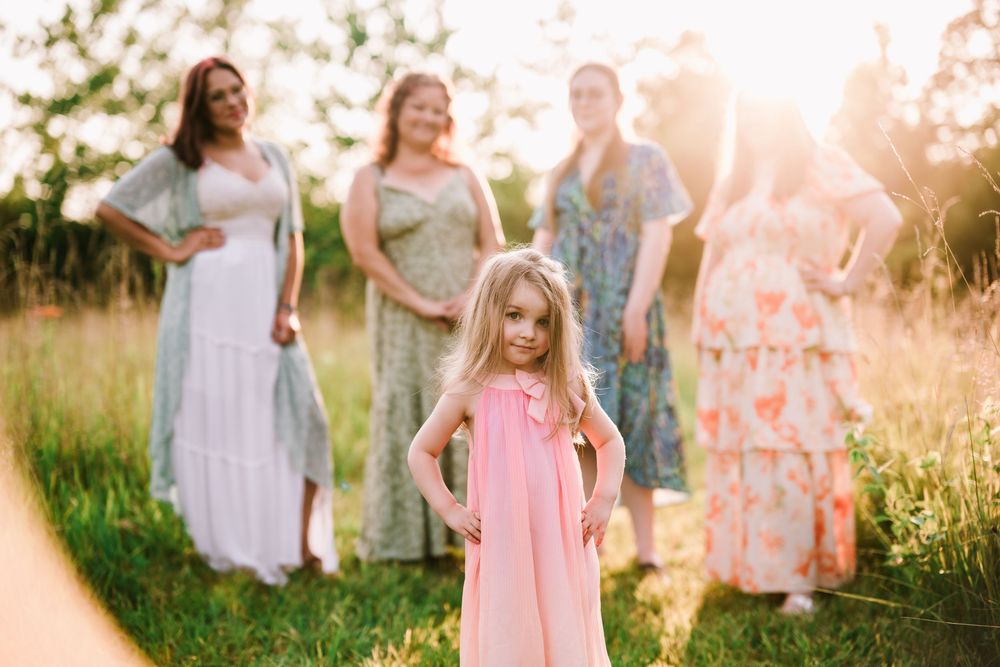 Dreamy summer portrait session in a sun-drenched field with soft pastel clothing.