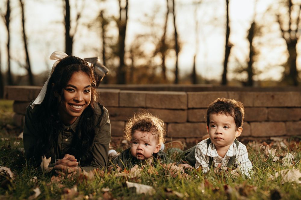 A group of children and adults play together outdoors during golden hour sunlight in a backyard setting.
