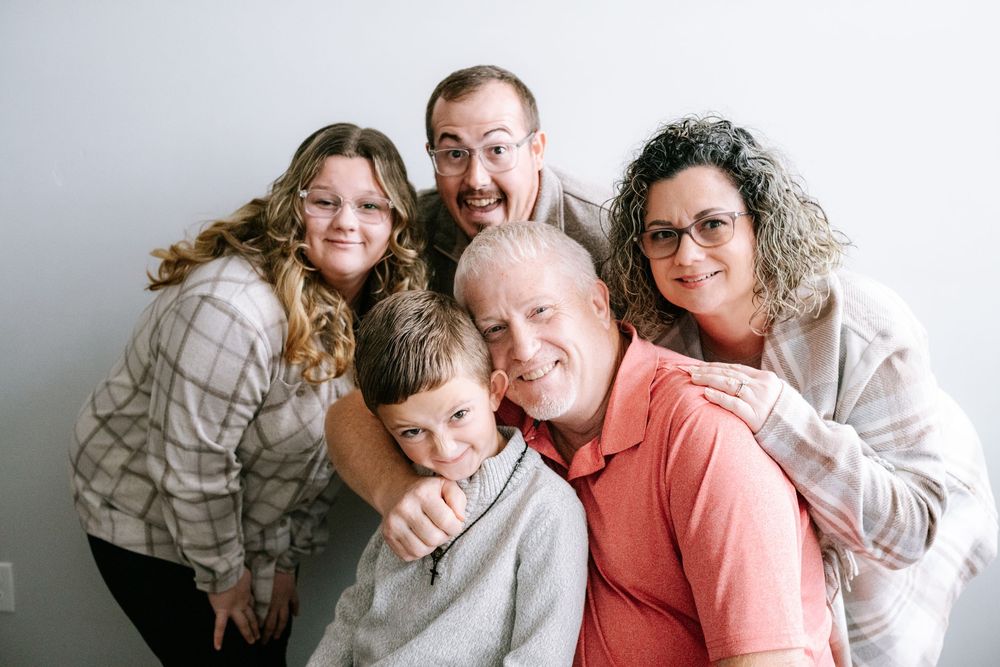 A series of candid family portraits showing tender moments and warm embraces against a light neutral background.