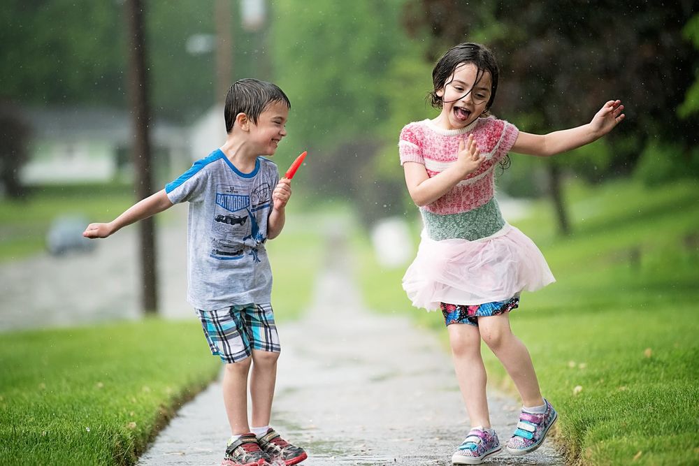 Children playing and running together on a wet path after rain.