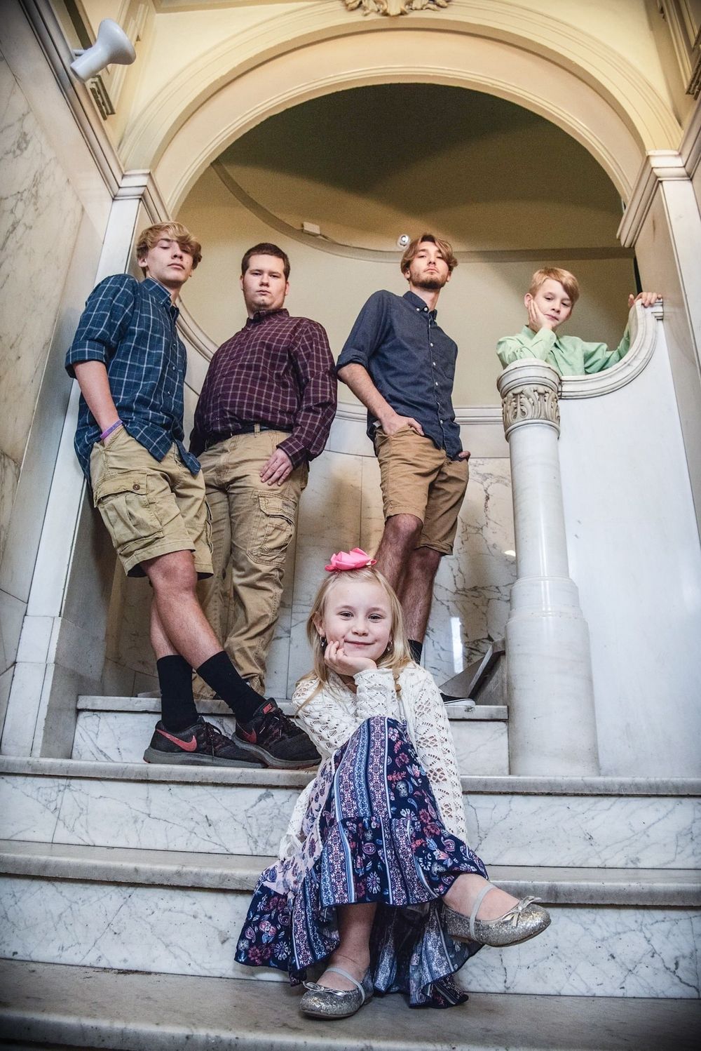 Artistic portrait on marble steps with people posed at different heights in casual attire.