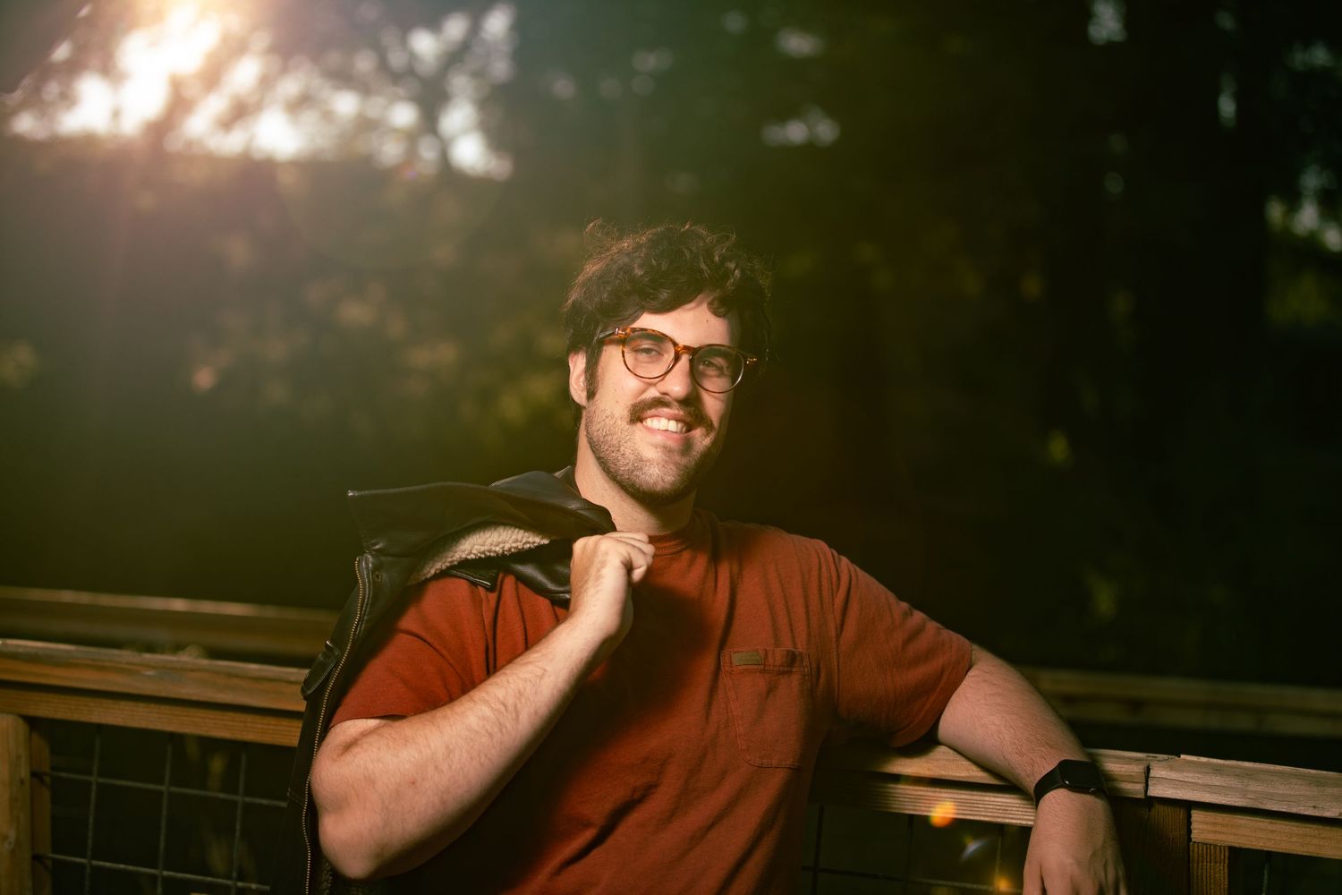 Casual outdoor portrait with wooden bench and natural lighting during golden hour.