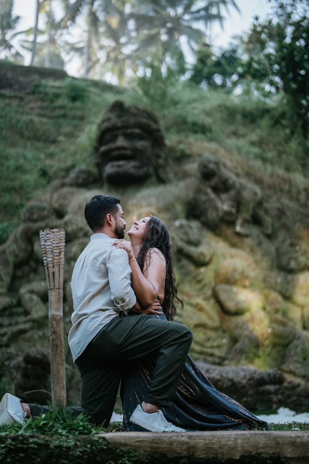 A tender moment between a couple sitting on a wooden bench against a backdrop of palm trees.