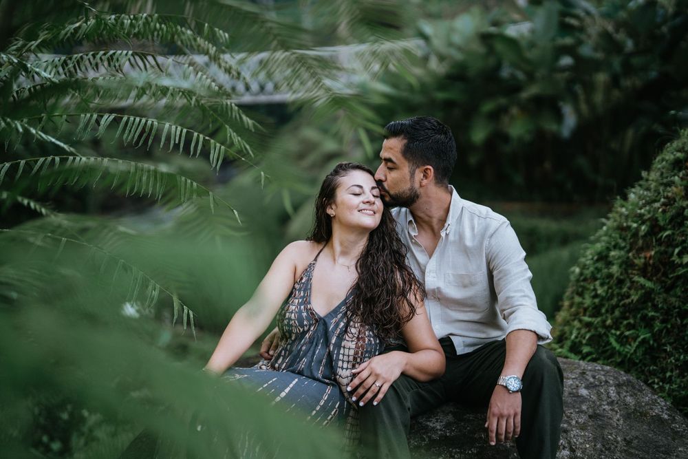 A couple shares tender moments while relaxing in a lush tropical garden setting.