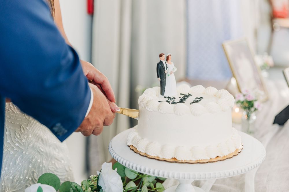 Wedding cake cutting ceremony at an elegant reception with white frosted cake on display.
