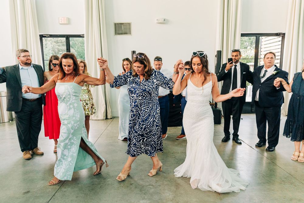 Wedding guests enjoying themselves on the dance floor at a modern reception venue with white walls and polished concrete floors.