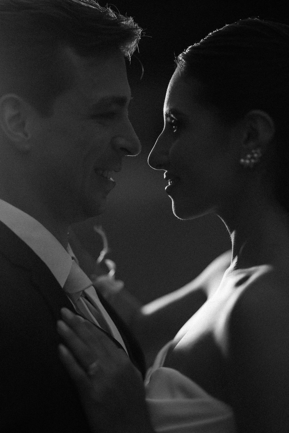 Black and white romantic wedding photos capturing intimate close-up moments between newlyweds in dramatic lighting.