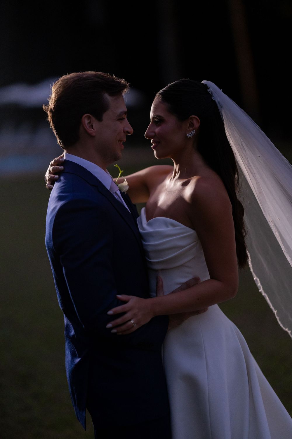 Romantic wedding couple sharing an intimate moment at dusk as they embrace in formal attire.