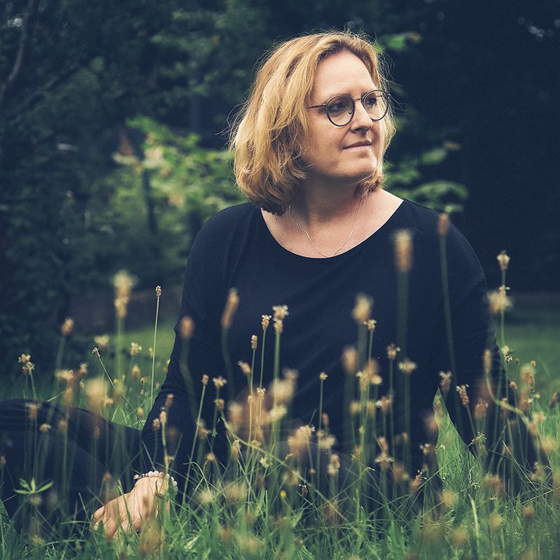 romantisches Portrait einer Frau im Gras sitzend und in die Ferne schauend Studiogarten Aurelia Schulz Bad Arolsen