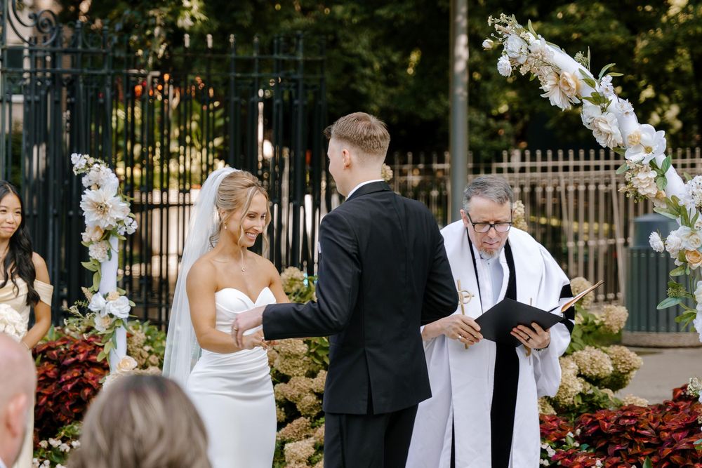 Wedding party celebrates with joyful expressions and white doves being released in an outdoor garden setting.