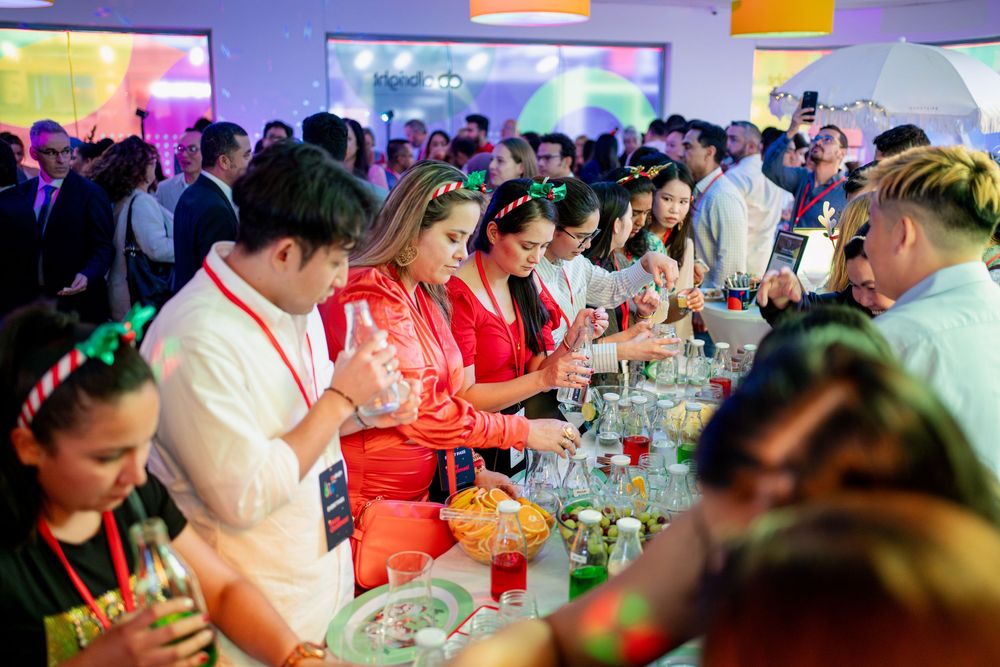 Large crowd gathered at tables for a social event under purple and red ambient lighting.