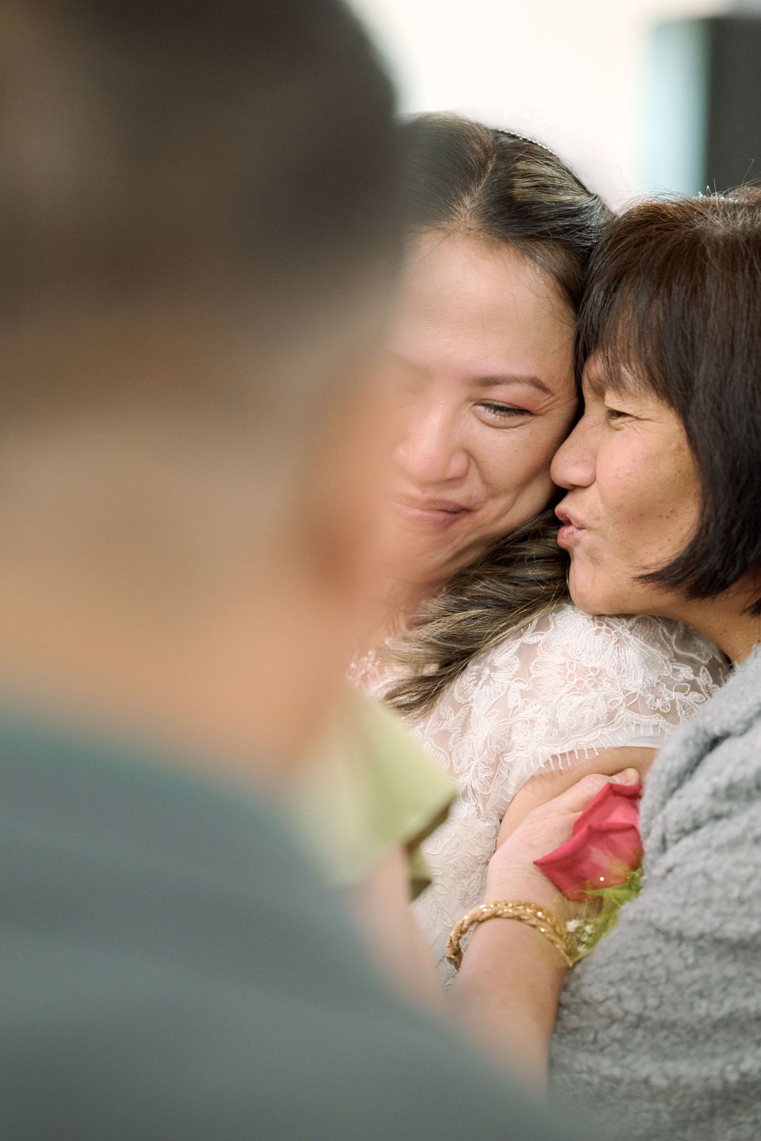Two people sharing a tender emotional moment embracing and smiling while wearing white and gray clothing.