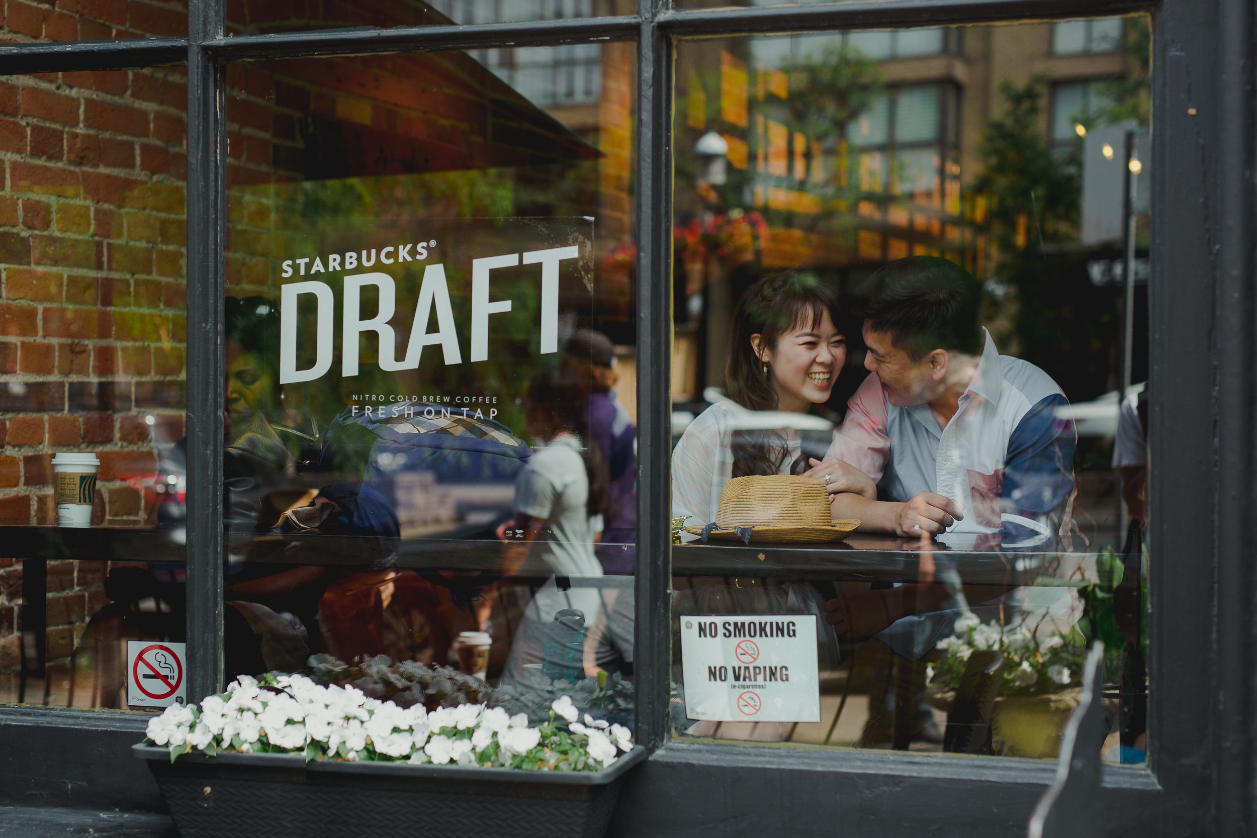 Cozy cafe storefront with outdoor seating and brick facade features string lights and floral window boxes.