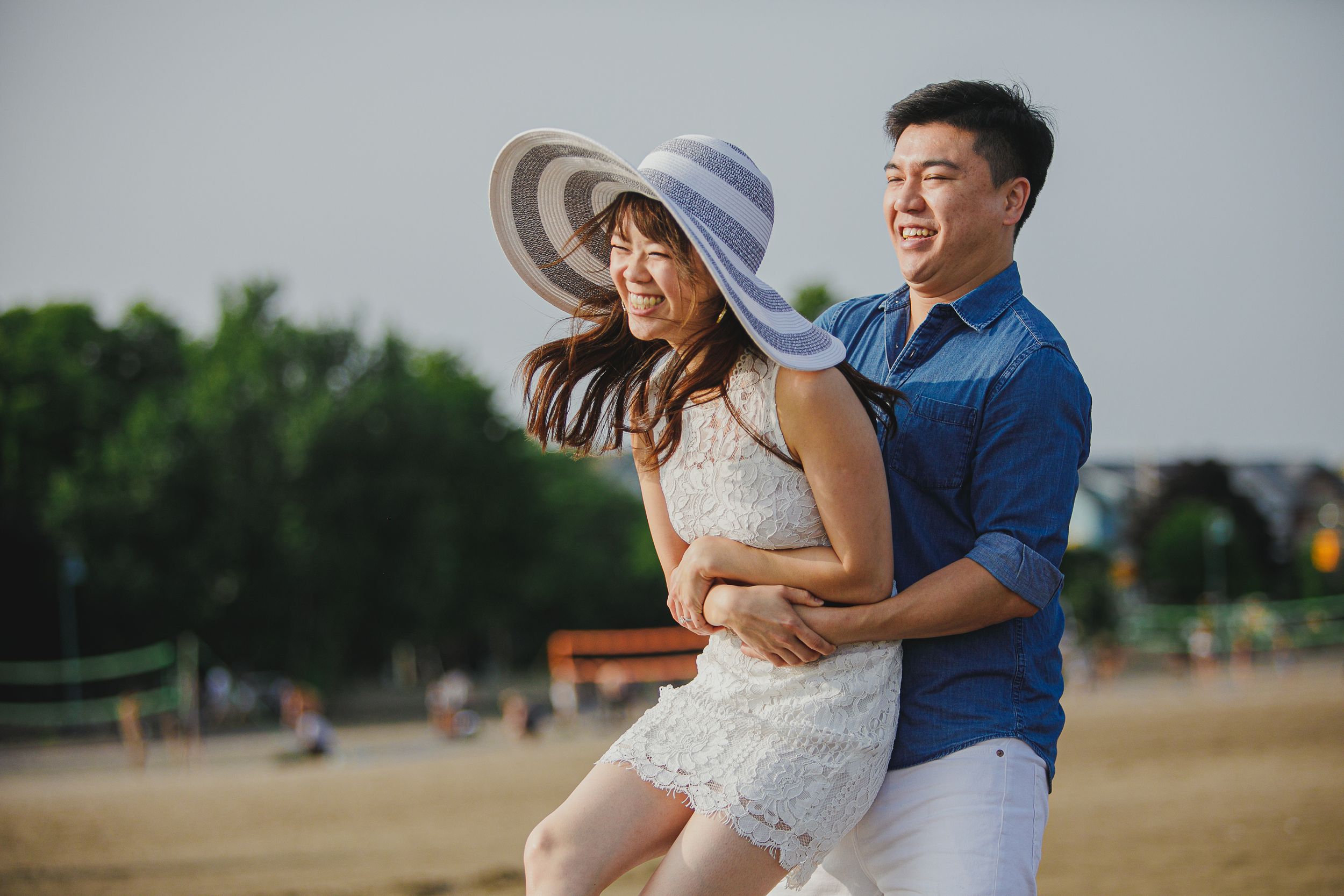 Couple embracing in a romantic outdoor photoshoot against a soft gray sky background.
