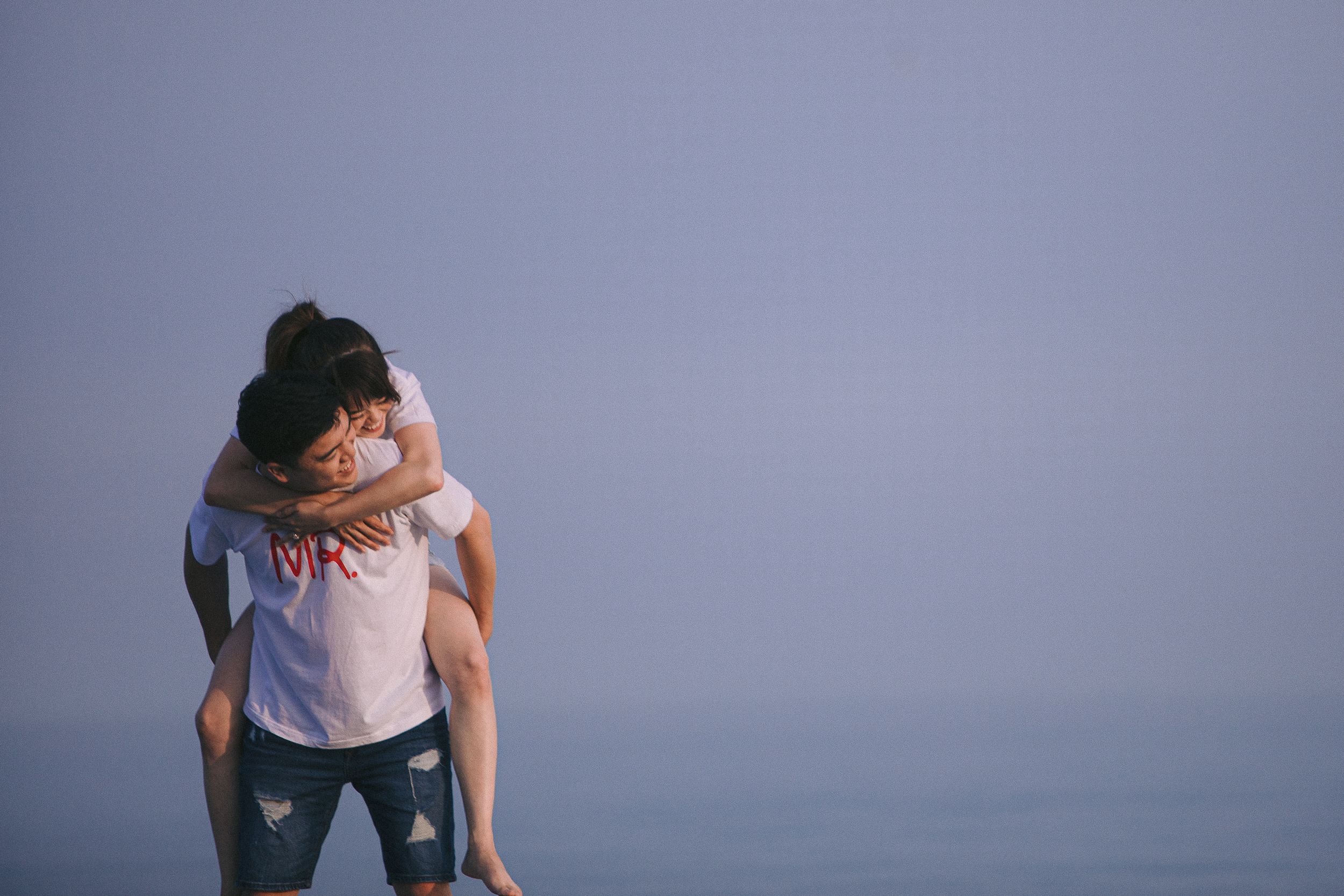 Figures embracing against a soft purple-tinted backdrop in a minimalist setting.