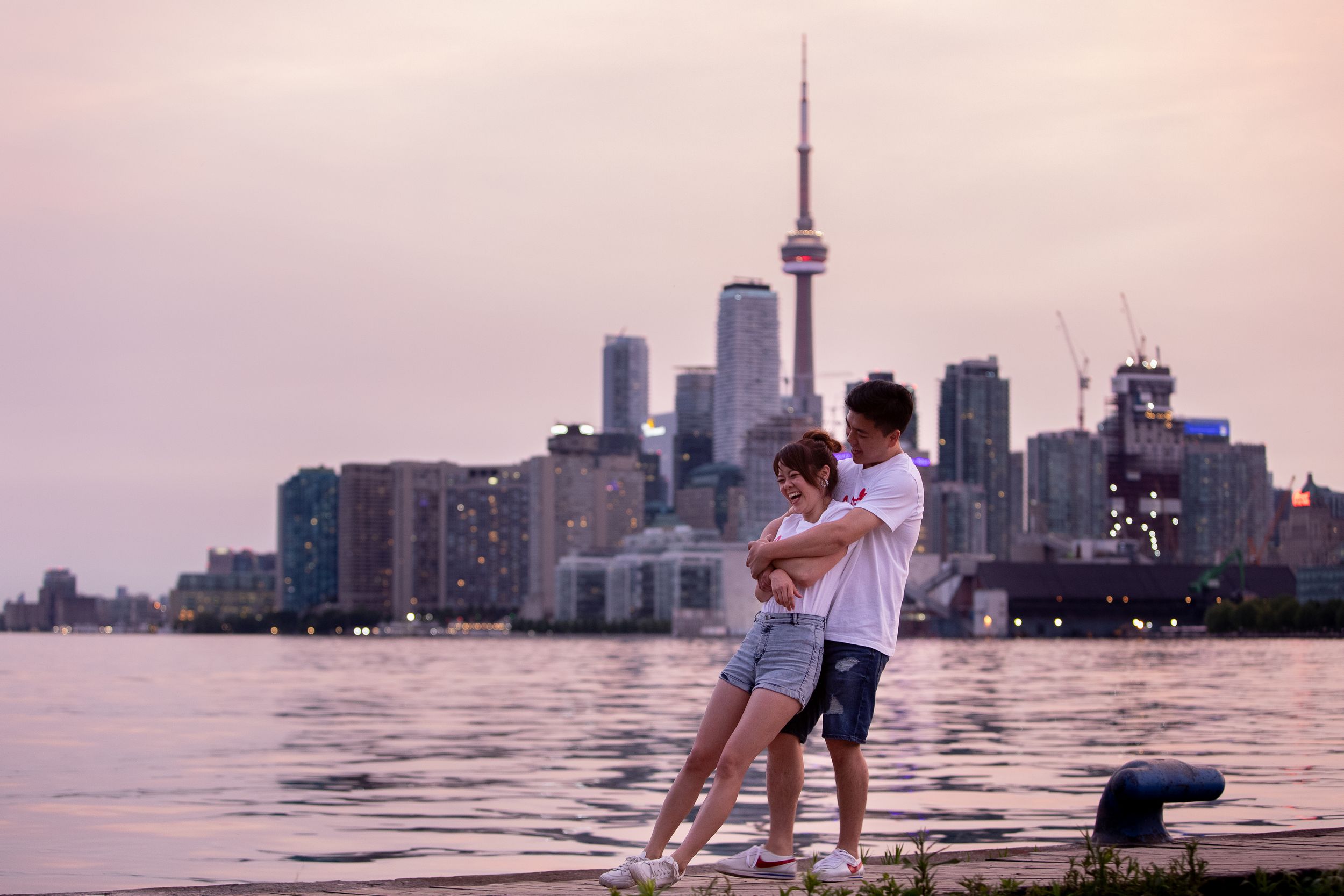 Silhouetted figures enjoy a sunset view of the Toronto skyline with CN Tower from the shores of Lake Ontario.