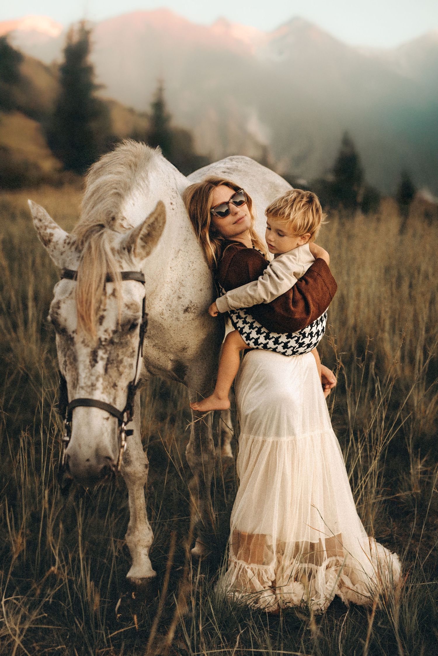 A dreamy photoshoot in a golden field features a white horse and someone in a flowing white dress at sunset. Javea photographer