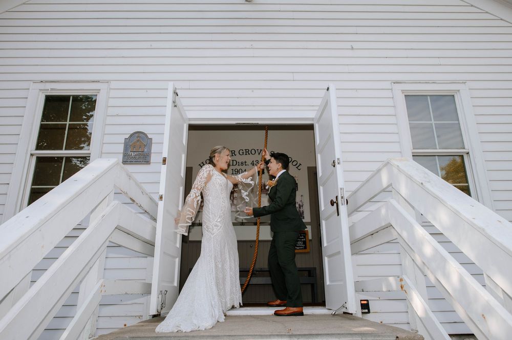 A wedding couple poses on white stairs in front of a white building during their special day.