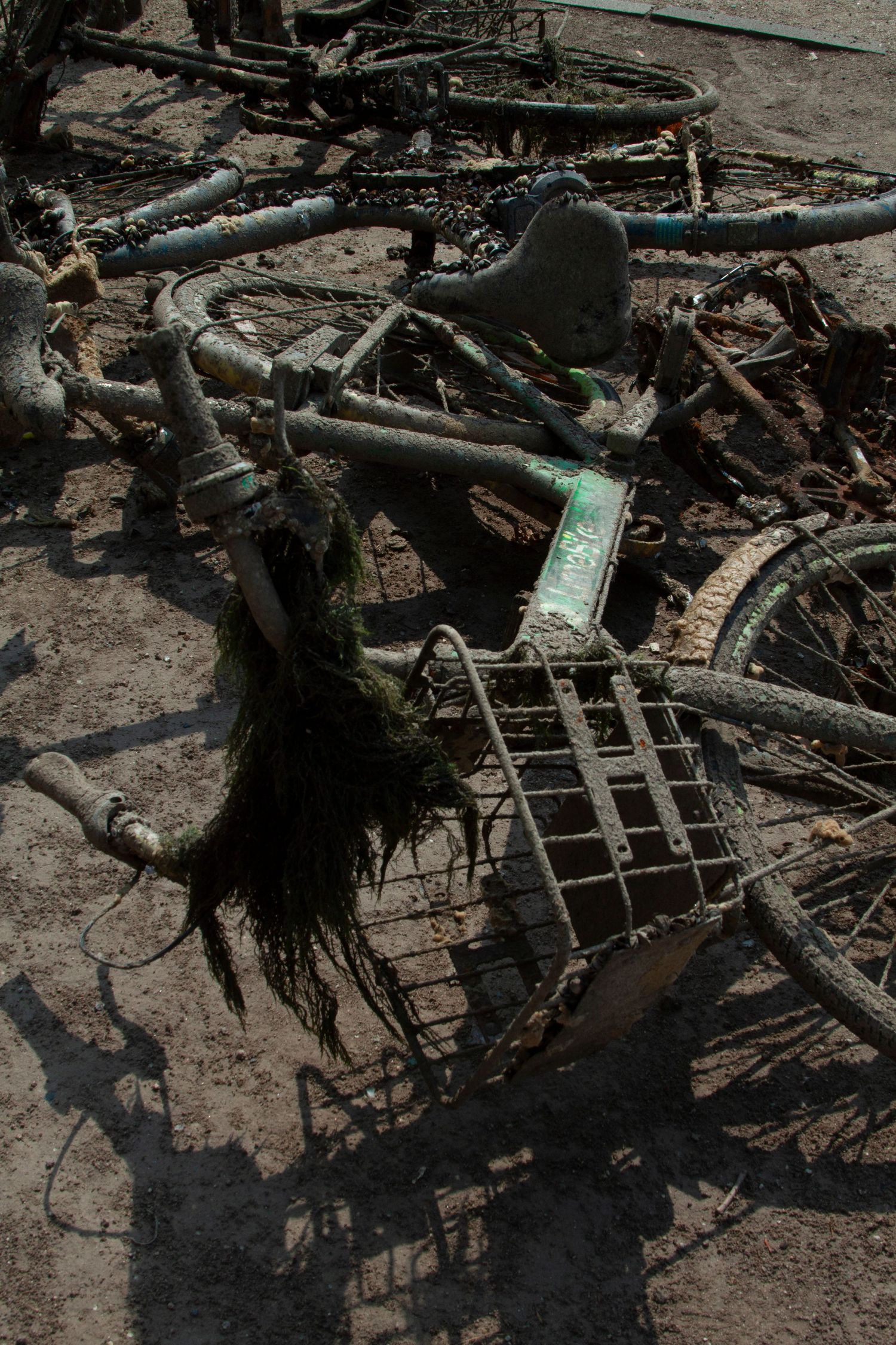 A close-up view of muddy debris and twisted metal fragments scattered on the ground after what appears to be storm damage.