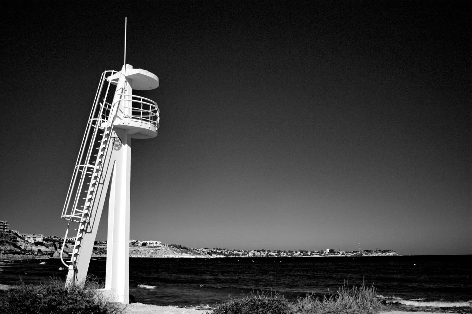 Turm zur Strandüberwachung am Strand von Campoamor in Spanien schwarz/weiß sehr kontrastreich mit Campo Roig im Hintergrund