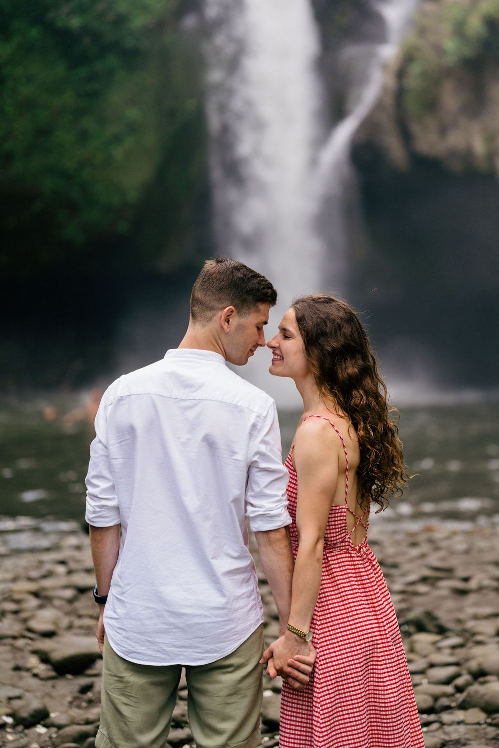 Couple sharing romantic moment in front of majestic waterfall.