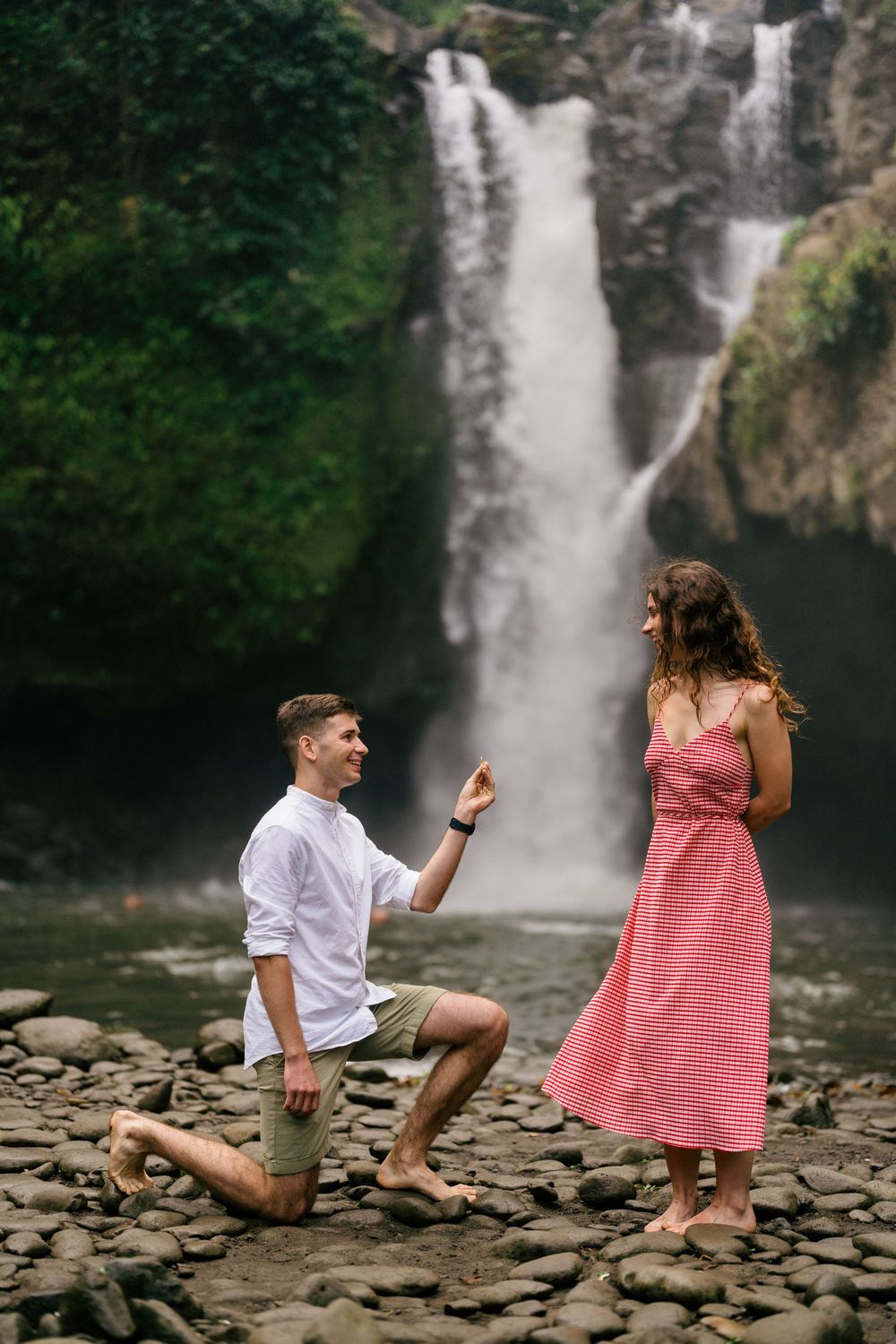 Surprise proposal moment captured at scenic waterfall location.
