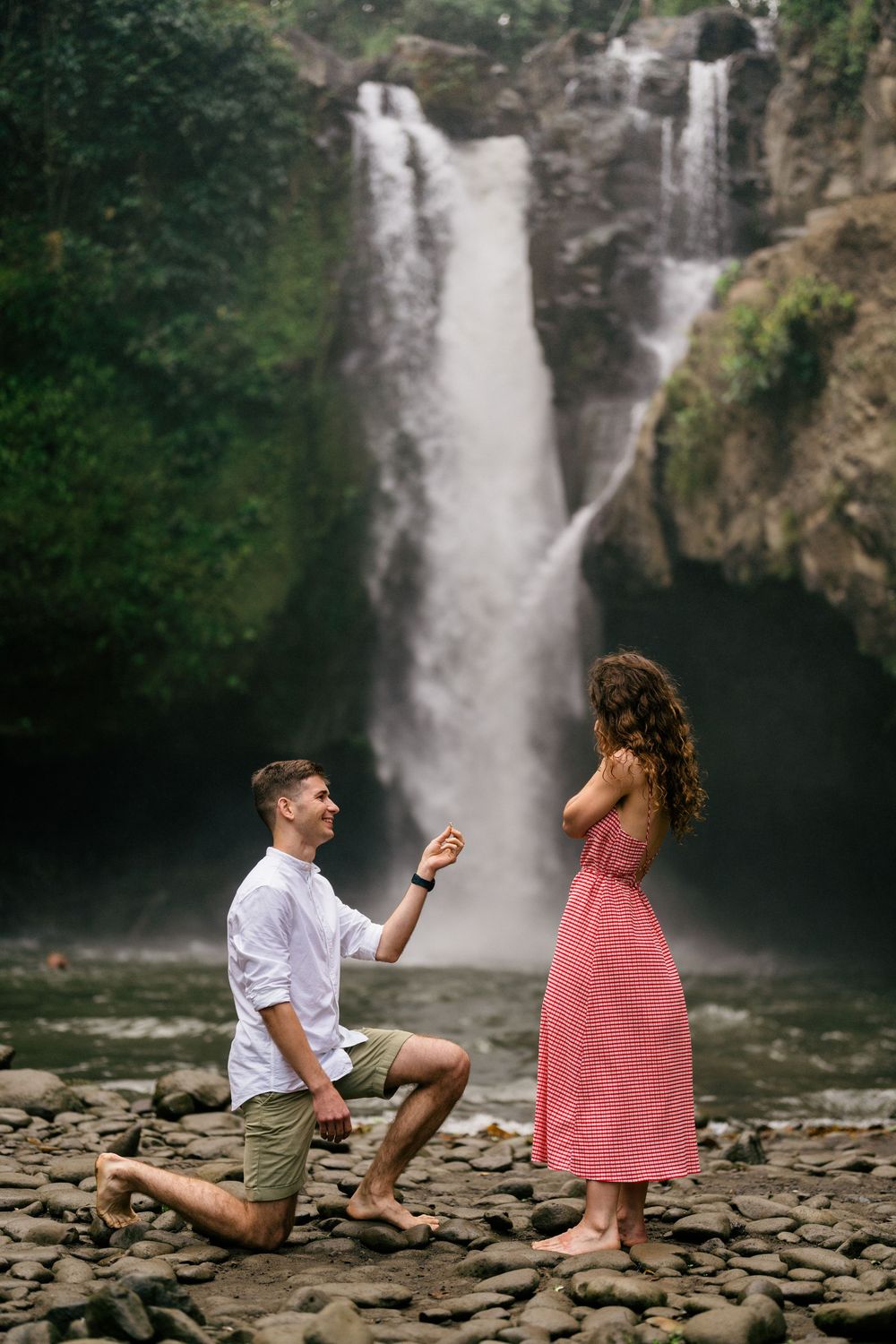 Marriage proposal scene with waterfall and rocky landscape.