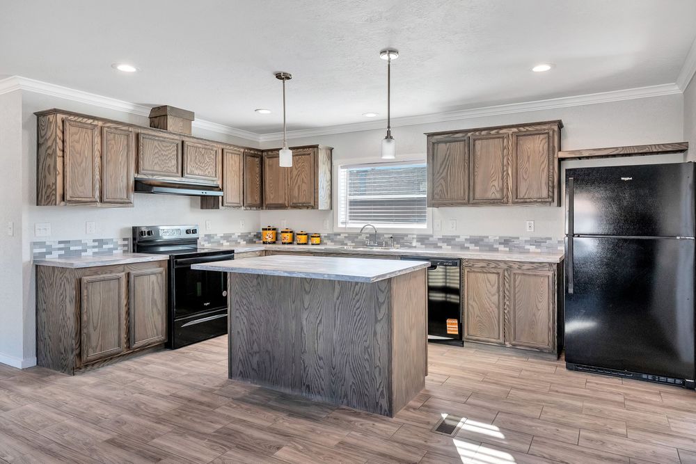 Modern kitchen interior with brown cabinets, black appliances, and light hardwood floors in an open concept layout.