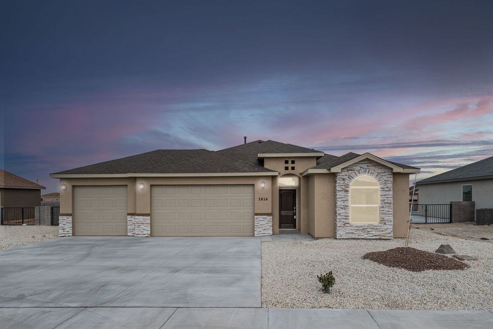 Modern single-story desert homes with beige stucco exteriors and gravel landscaping under a dramatic sunset sky.
