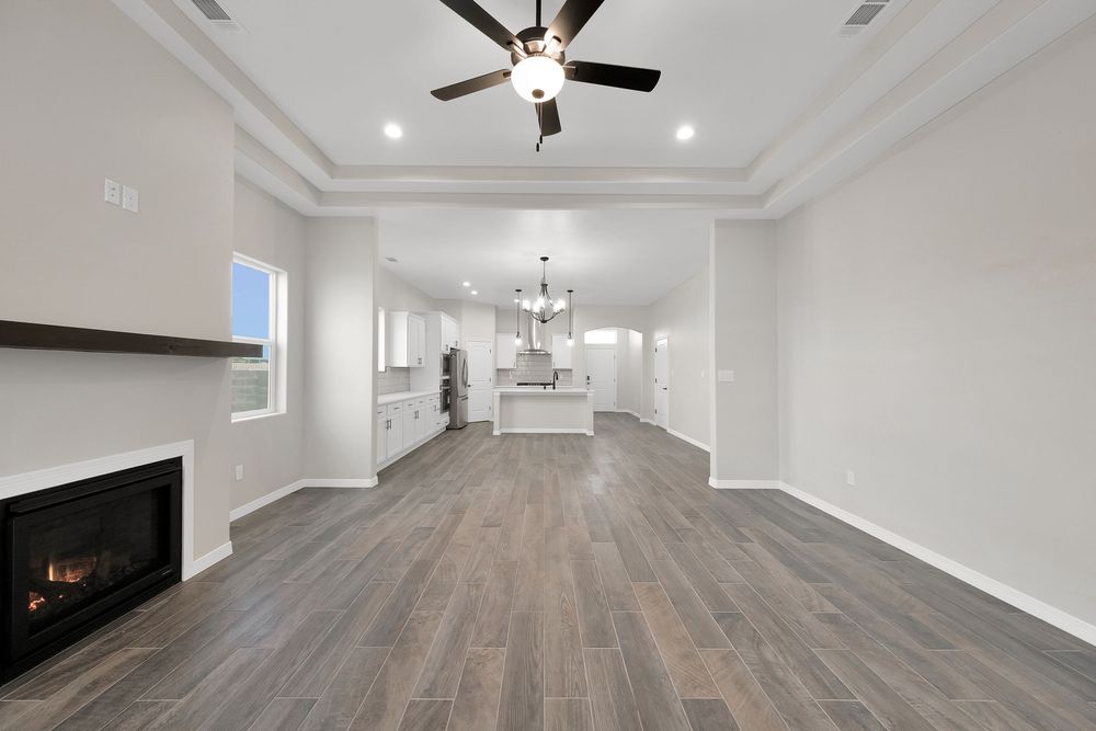 Modern white basement hallway with recessed lighting, ceiling fan, and light wood flooring leads to open living space.