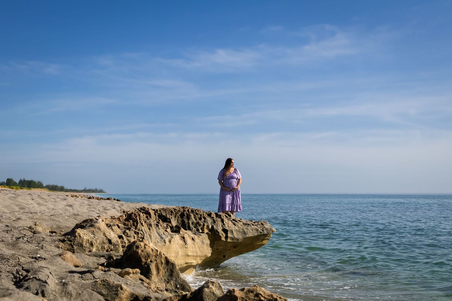 Rocky coastline meets turquoise ocean waters under bright blue sky.