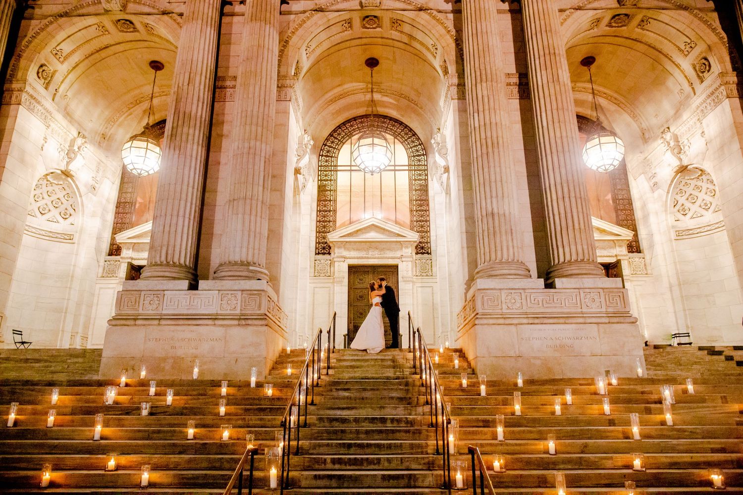 Candlelit marble staircase in an ornate cathedral-like interior with soaring columns.