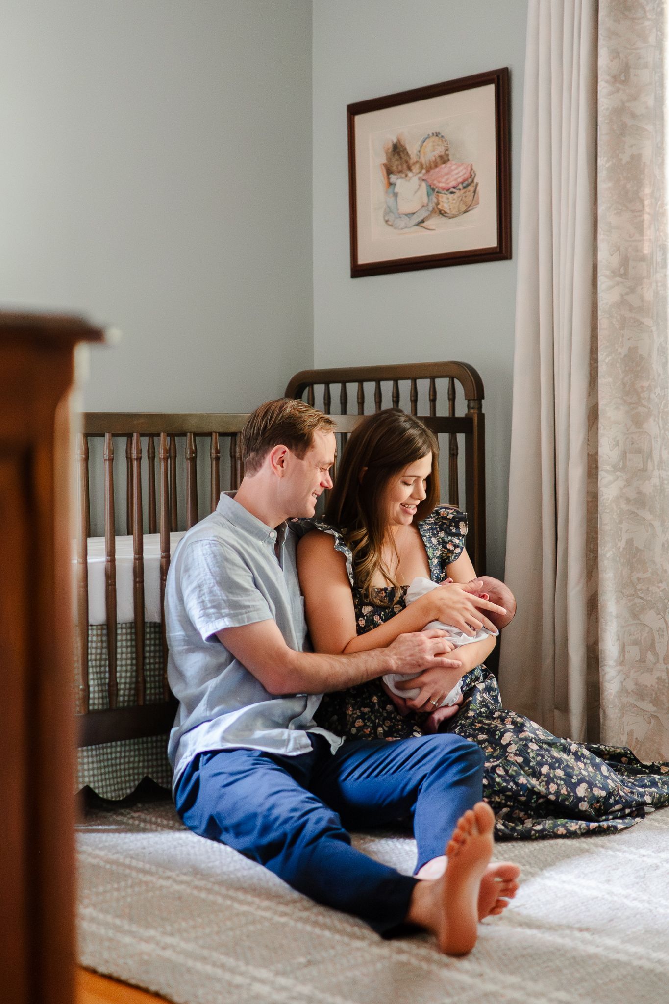 Couple sitting together on bed in casual clothes looking down at something while relaxing at home.